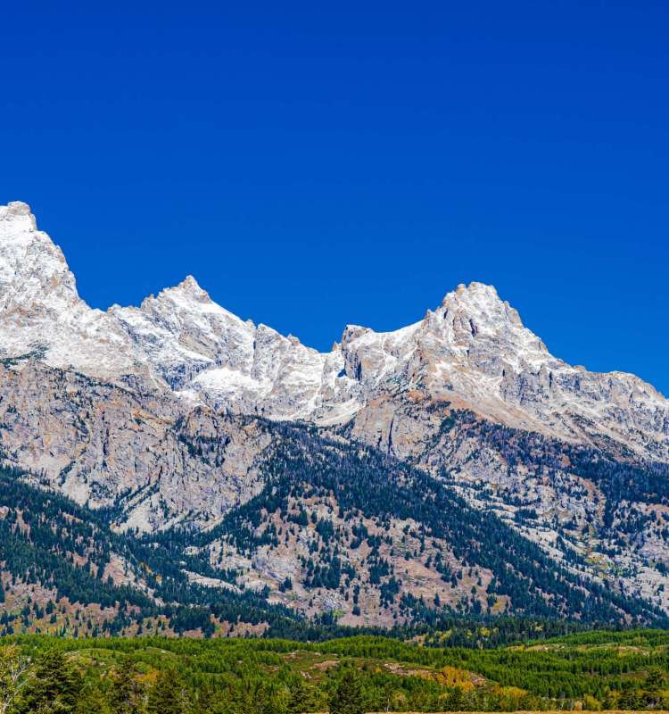 The image shows a view of some of the Teton Range peaks covered with a dusting of snow